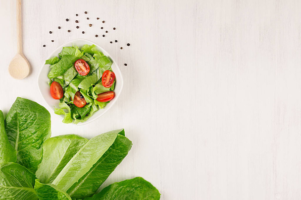 Healthy vegetarian salad of fresh tomatoes and spinach on white wood background, top view, copy space. - Valokuva, kuva