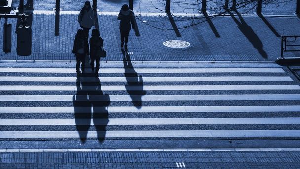σιλουέτα άνθρωποι περπατούν για πεζούς διάβαση πεζών στην οδό διασταύρωση της πόλης επιχείρηση κατά το ηλιοβασίλεμα το βράδυ με τη σκούρα σκιά των ανθρώπων στο δρόμο (κορυφαία εναέρια άποψη) - Φωτογραφία, εικόνα