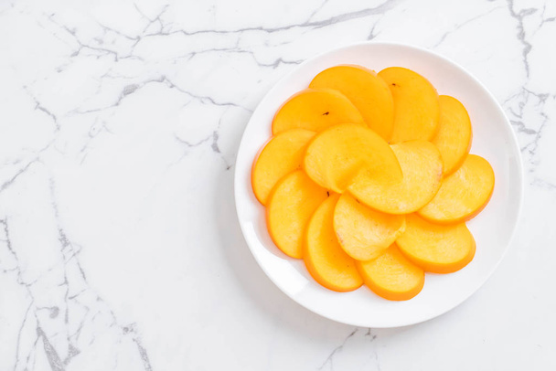 sliced persimmon on plate - Фото, изображение