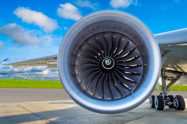 Motor des modernen Flugzeugs aus nächster Nähe und die blauen Wolken am Himmel. - Foto, Bild