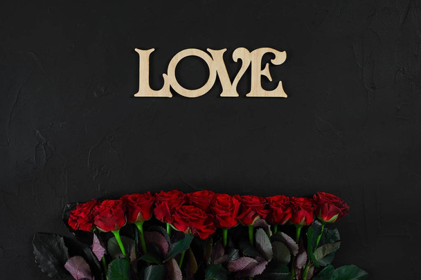 Red roses flowers with wooden word LOVE on black background with - Fotografie, Obrázek