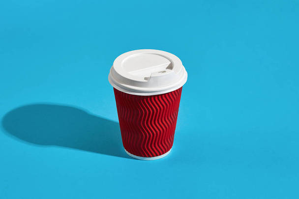 Hot coffee in red paper cup with white lid on blue background wi - Photo, Image