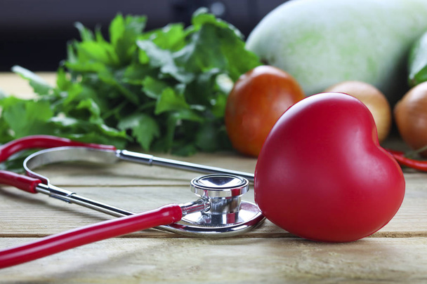 Conceito saudável de lareira, legumes e frutas com folha de ervas e ouvido médico sobre fundo de madeira
 - Foto, Imagem