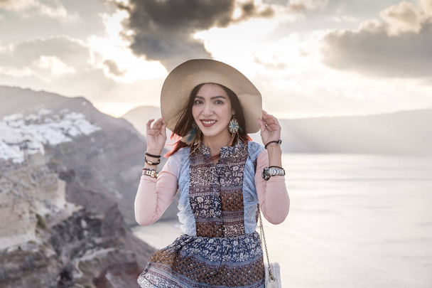 Azjatka w kapeluszu stojąca w Santorini, Grecja - Zdjęcie, obraz