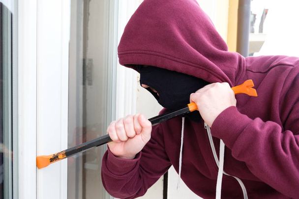 Ladrón con capucha forzando ventana obturador bloqueo
 - Foto, Imagen
