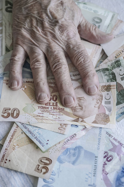 faltige Hand einer älteren Person auf türkischen Lira-Banknoten - Foto, Bild
