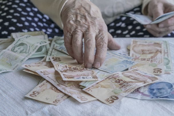 Manos arrugadas de una persona mayor que cuenta billetes de lira turcos
 - Foto, Imagen