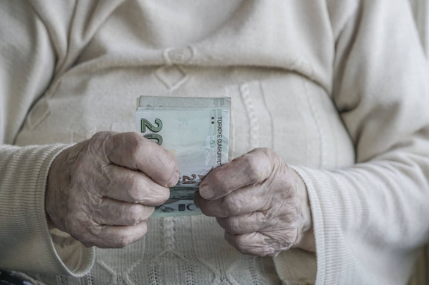 Mano arrugada de una persona mayor con billetes de lira turca
 - Foto, imagen