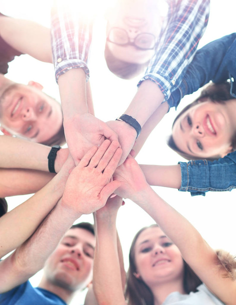 grupo de adolescentes sorridentes com as mãos em cima uns dos outros
 - Foto, Imagem