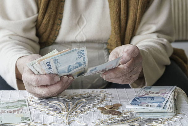 Primeros planos de las manos arrugadas de una mujer mayor que cuenta los billetes turcos de Lira
 - Foto, imagen