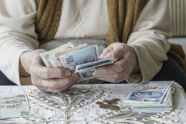 Cerrar las manos arrugadas de una mujer mayor contando billetes turcos de Lira
 - Foto, Imagen