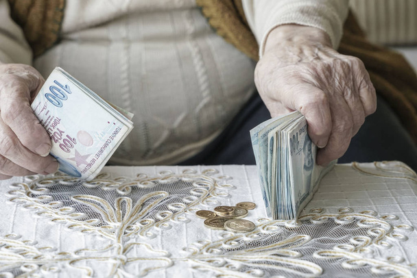 Nahaufnahme faltige Hände einer Seniorin, die türkische Lira-Banknoten zählt - Foto, Bild