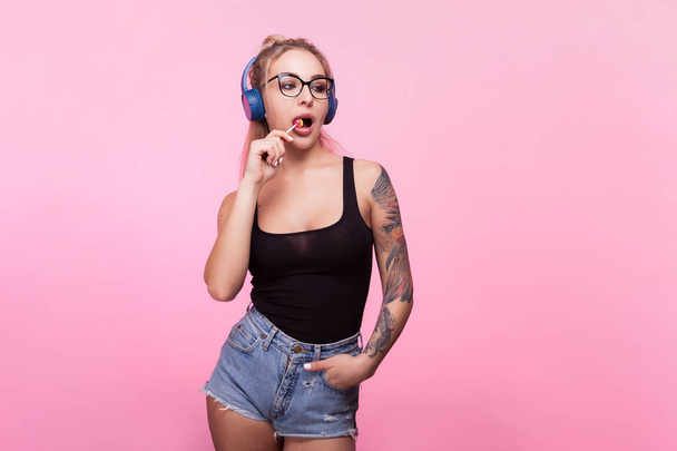 Sexy woman listening to music and having a lollipop - Foto, Imagem