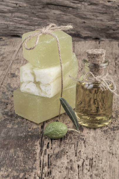natuurlijke olijfolie zeep bars en olie fles op houten tafel - Foto, afbeelding