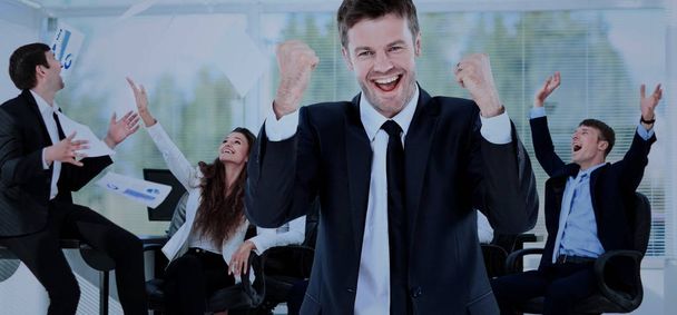 Happy businessman standing in front of his colleagues in office - Photo, Image