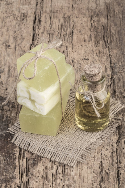 мыло из натурального оливкового масла и бутылка оливкового масла на деревянном столе
 - Фото, изображение