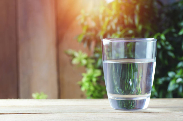 vidro de água potável sobre fundo de madeira e natureza verde
 - Foto, Imagem