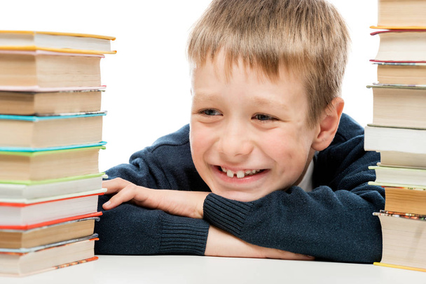 портрет смеющегося школьника крупным планом среди груды книг
 - Фото, изображение