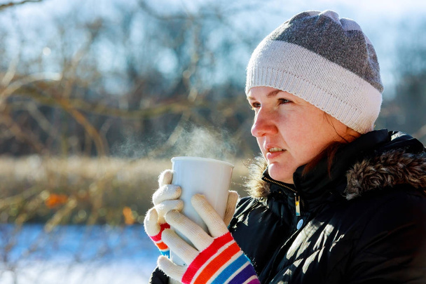 Mooie jonge vrouw drinken van hete thee op een koude winterdag - Foto, afbeelding