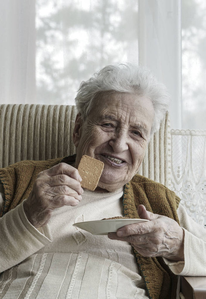 Gelukkig senior vrouw koekjes eten - Foto, afbeelding