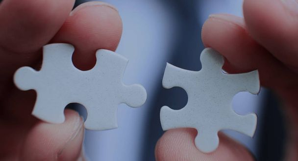 Businessman holding two blank white puzzle pieces in his hands conceptual of solving a problem, growth and development. - Фото, изображение