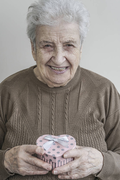 senior woman holding heart shaped gift - Photo, Image