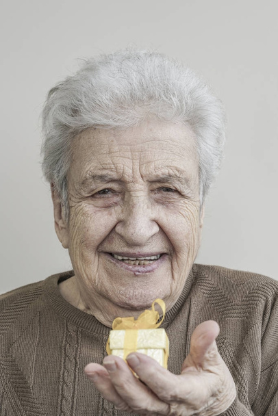 Femme âgée tenant un petit cadeau
 - Photo, image