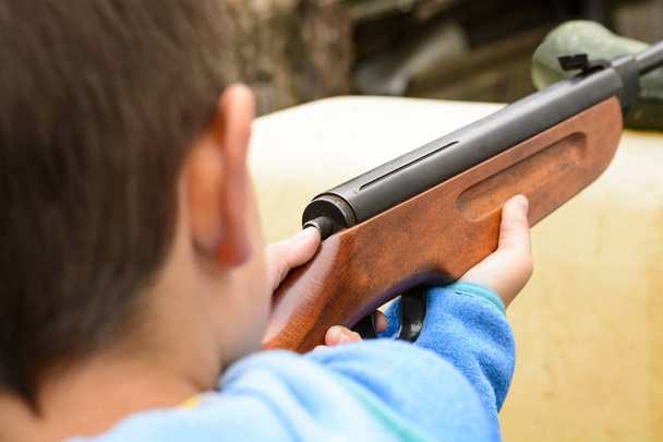 A little boy shooting from an air rifle to a target - Fotó, kép