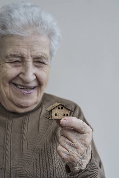 senior woman holding a small wooden house - 写真・画像