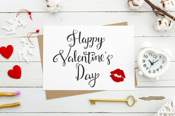 Happy Valentines Day lettering on vintage paper sheet with golden key, heart shaped alarm clock,. red hearts on white wooden background. Flat lay. Mockup lettering - Valokuva, kuva