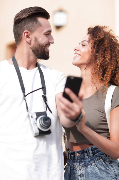 Smiling couple using smart phone together in city - Photo, Image