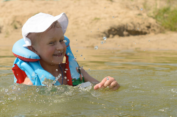 Ein fünfjähriger Junge in Schwimmweste badet im See. - Foto, Bild