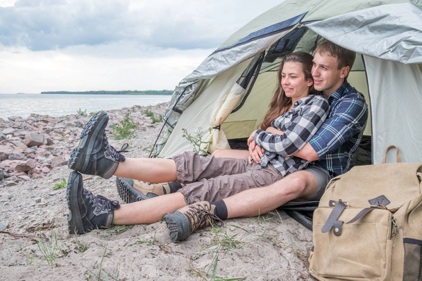 Happy loving couple resting near tent in the woods - Photo, Image