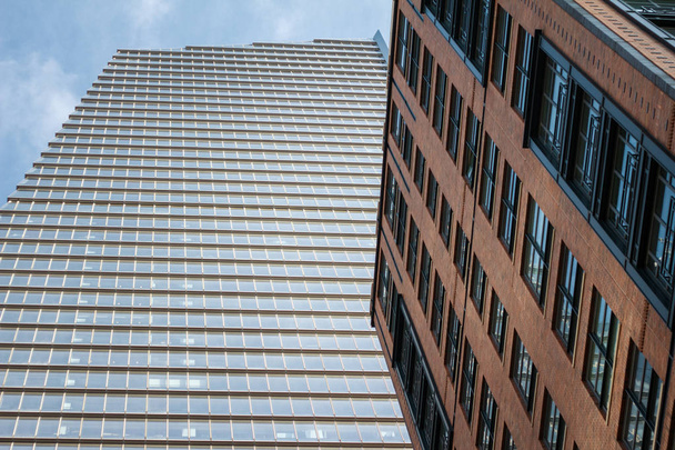 Нижний вид на современный небоскреб и кирпичное здание
 - Фото, изображение