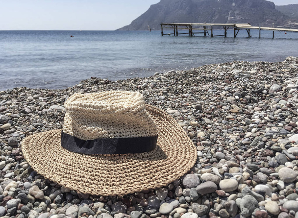 A straw hat on a pebbly beach in Greece - Photo, Image