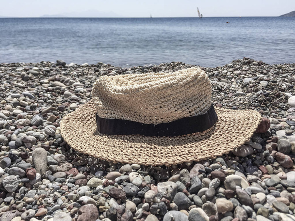 Egy kavicsos strandon nyáron szalma kalap - Fotó, kép