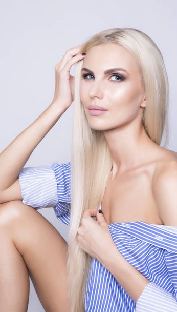 Sexy woman sitting in business shirt. Long platinum blonde hair. - Foto, Imagen