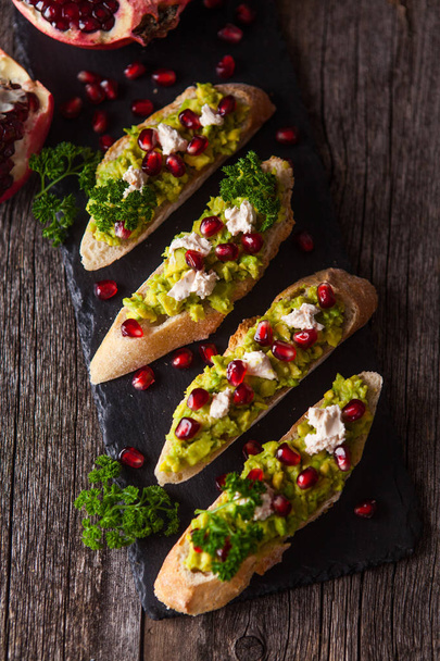 Toast with avocado and pomegranate on wooden table - Foto, immagini