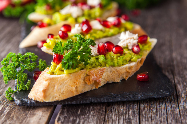 Toast with avocado and pomegranate on wooden table - Fotografie, Obrázek