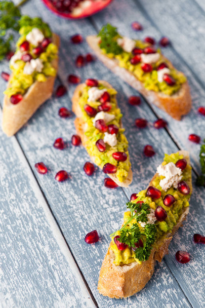 Toast with avocado and pomegranate on grey table - Фото, зображення