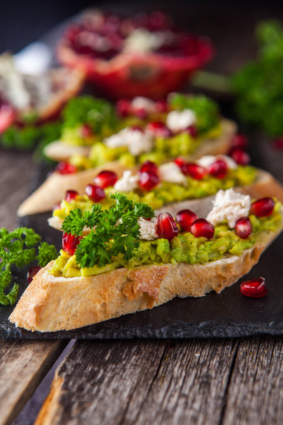 Toast with avocado and pomegranate on wooden table - Photo, Image