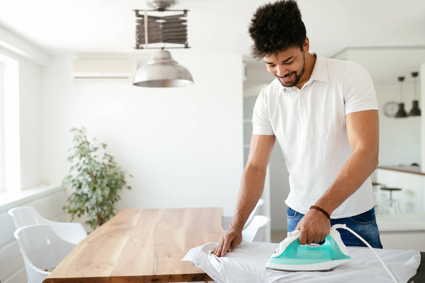 Young Happy Man Ironing Clothes - 写真・画像