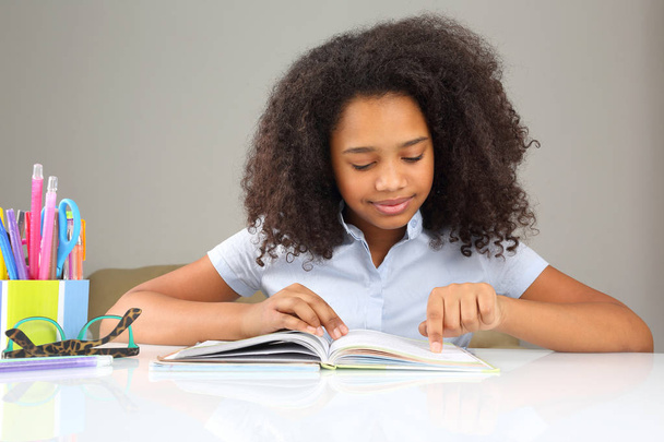 темнокожая школьница читает книгу о домохозяйствах
 - Фото, изображение