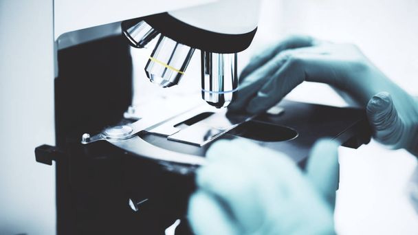 La main d'un scientifique en blouse de laboratoire se prépare à commencer une recherche au microscope dans un laboratoire
. - Photo, image