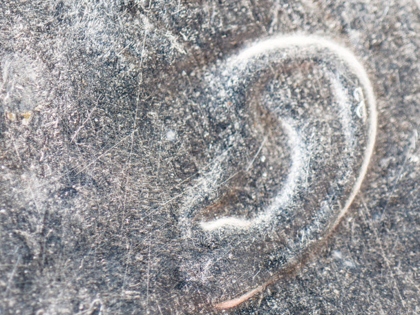 Μια ακραία closeup μακροεντολή λεπτομέρεια μικροσκοπική εικόνα του αυτιού με ασημένια ξεπερασμένο μας 10 σεντ νομίσματος πενηντάρικο συμπεριλαμβανομένων κηλίδες και ατέλειες. - Φωτογραφία, εικόνα