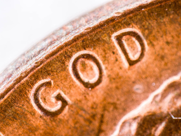 eine extreme Nahaufnahme Makrodetailmikroskopisches Bild einer verwitterten Kupferpfennig-Münze mit Kratzern, Kratzern, Kratzern und anderen Makeln oder Unvollkommenheiten und fokussiert auf das Wort Gott. - Foto, Bild