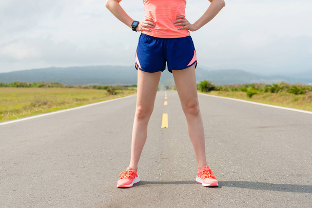 жіночий марафон бігунка стоїть на заміській дорозі
 - Фото, зображення