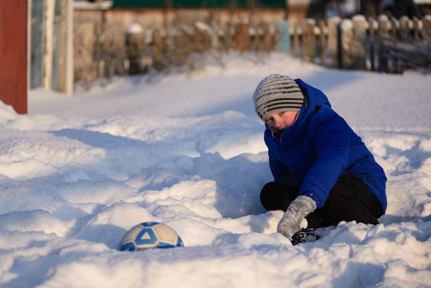 Uczniak chłopiec kopie piłkę grać w football zima na s - Zdjęcie, obraz