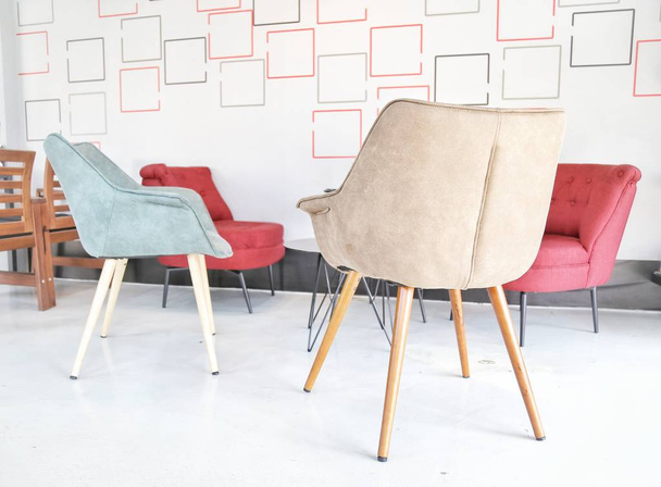 Fehér nappali színes (piros, termesztett, kék) székek, kisasztal és fehér, sárga, piros részleteket minta grafikai díszítések a tapéta modern házban. - Fotó, kép