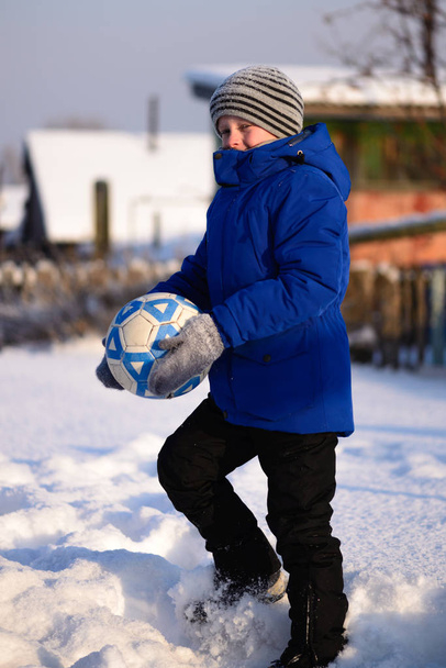 Хлопчик-школяр кидає м'яч, граючи в зимовий футбол на s
 - Фото, зображення